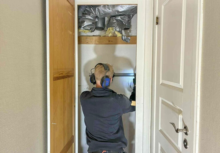En installatör hos Köpman Ventilation monterar fästningsanordning.